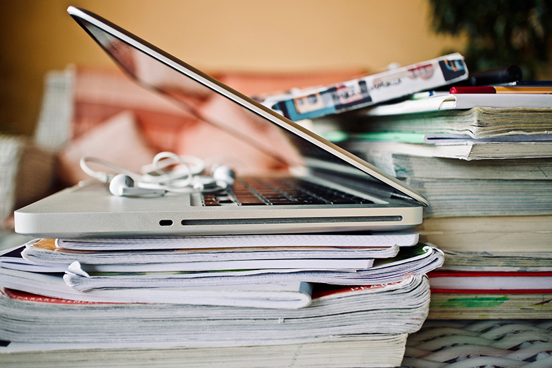 Laptop liegt auf einem Stapel von Katalogen und Zeitschriften